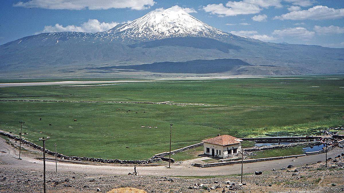 Snow-capped Mount Ararat rising above a green plain on the Turkish side